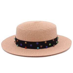 Détail de la texture d'un chapeau de paille rose avec ruban noir orné de gemmes