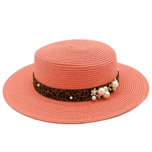 Detail of pink straw hat featuring leopard print band with white pearls and flower