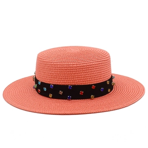 Détail d'un chapeau canotier rose avec ruban en satin noir et strass multicolores