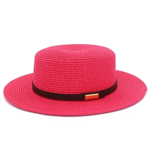 Détail du tissage d'un chapeau canotier rose avec ruban noir et boucle dorée