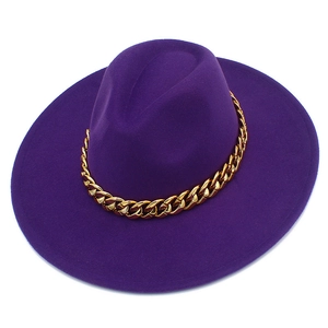 Détail d'un chapeau fedora violet à large bord avec une chaîne en métal doré décorative