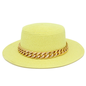 Détail d'un chapeau de paille jaune clair orné d'une chaîne dorée élégante et moderne