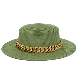 Gros plan d'un chapeau de paille vert olive avec une chaîne dorée décorative épaisse