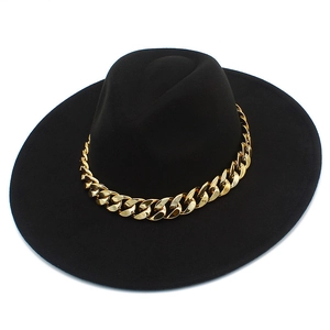 Détail d'un chapeau fedora noir à large bord avec une grosse chaîne en métal doré chic