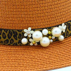 Orange straw sun hat featuring a leopard print band with pearls and floral accents