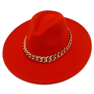 Détail d'un chapeau fedora rouge à larges bords avec une grosse chaîne en métal doré