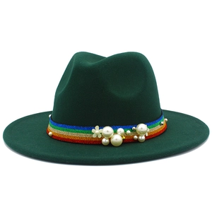 Close-up of dark green fedora featuring rainbow woven band with pearls and floral accent