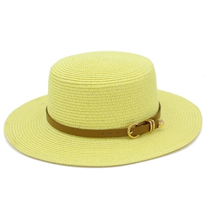 Close-up of yellow woven straw hat featuring a brown leather band and gold heart buckle