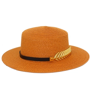 Detail of caramel straw hat with black leather band and golden leaf metal accessory