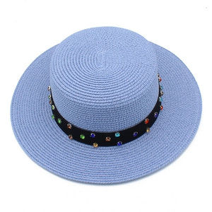 Détail du tissage d'un chapeau de paille bleu avec bande ornée de strass colorés