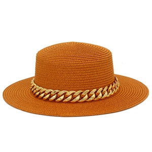Gros plan sur un chapeau de paille orange vif avec chaîne dorée et texture tressée fine