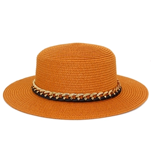 Détail du chapeau de paille orange avec chaîne décorative en métal doré et noir