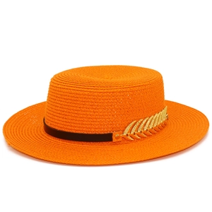 Detailed macro view of vibrant orange straw boater hat with black band and gold leaf