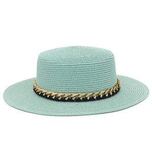 Détail du chapeau de paille vert menthe avec texture fine et boucle en chaîne dorée décorative