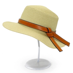 Detail of straw sun hat featuring brown leather band with white contrast stitching