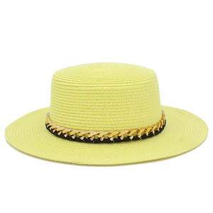 Détail d'un chapeau de paille avec chaîne dorée luxueuse et ruban en cuir noir chic