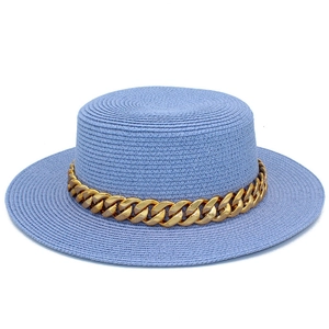 Détail d'un chapeau de paille bleu clair avec chaîne en métal doré et bord large plat