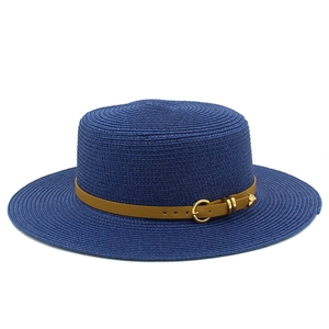 Close-up of blue straw boater hat featuring a brown leather band and gold buckle detail