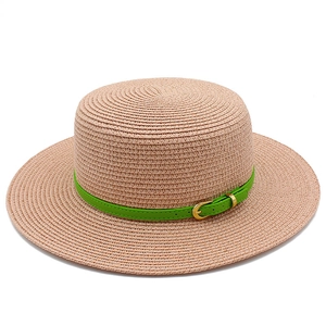 Close-up of pink straw hat featuring a vibrant green leather belt and gold buckle