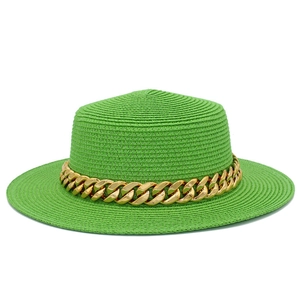 Détail d'un chapeau de paille vert avec une grosse chaîne dorée et une texture tissée