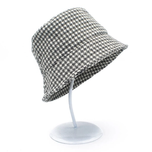 Detail shot of black and white houndstooth bucket hat on a white metal display stand