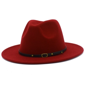 Détail d'un chapeau fedora rouge en laine avec ruban noir et rivets dorés