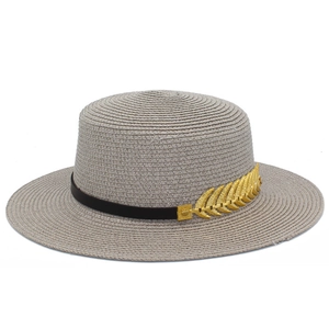 Close-up of flat top straw sun hat with black leather band and gold leaf decoration