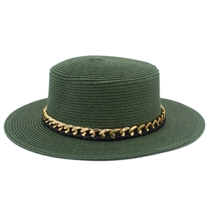 Détail de la texture de paille tressée et du ruban chaîne dorée sur ce chapeau vert