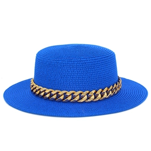 Détail d'un chapeau de paille bleu avec chaîne décorative en métal doré sur fond blanc