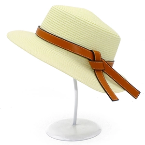 Close-up of woven straw hat featuring brown leather band with simple flat knot detail