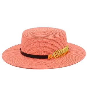 Close-up of coral pink woven straw hat with black leather band and gold feather detail