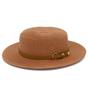 Close-up of woven straw sun hat with brown leather band and heart buckle detail