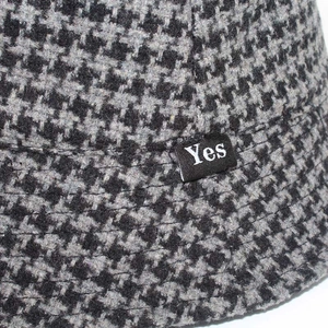 Detailed macro view of the houndstooth fabric texture and Yes label on the bucket hat