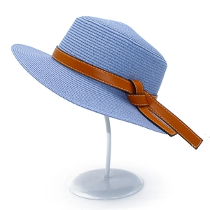 Detail of light blue woven sun hat featuring broad wavy brim and brown leather band detail