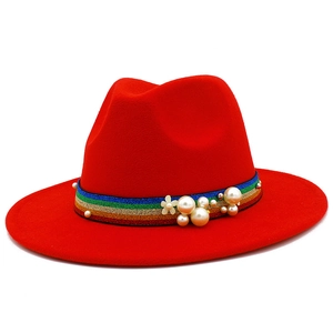 Detail of red fedora hat featuring rainbow glitter band with white pearls and flower