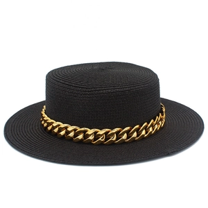 Détail d'un chapeau canotier noir avec une décoration élégante de chaîne dorée épaisse