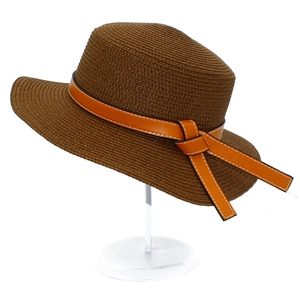 Detailed weave texture of coffee straw hat with orange leather bow decoration