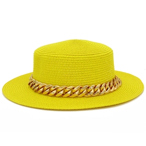 Détail d'un chapeau de paille jaune avec une chaîne dorée élégante et un bord plat