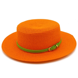 Detail of orange straw hat featuring a woven texture and green belt with gold buckle