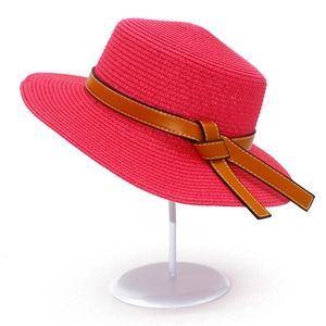 Detail of rose red straw hat with brown synthetic leather band and decorative knot