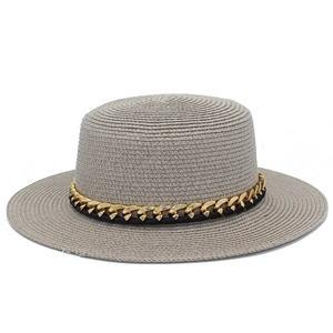 Détail d'un chapeau de paille gris avec chaîne dorée et ruban tissé noir élégant