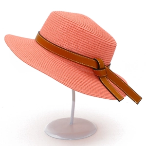 Detailed texture of coral pink straw sun hat with elegant brown leather decorative band