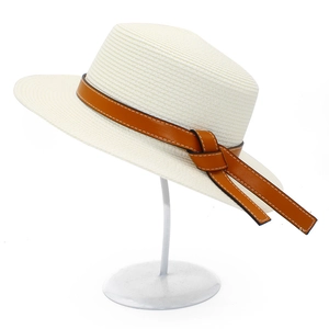 Detail of cream straw boater hat featuring a brown leather band with contrast stitching