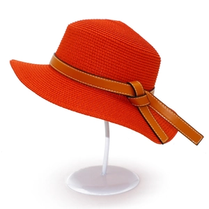 Orange woven straw sun hat with brown leather band and stitching detail on white stand