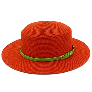 Detail of orange straw sun hat with green leather band and golden metal buckle
