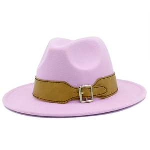 Detail of pink wool fedora hat featuring a brown leather band and gold metal buckle
