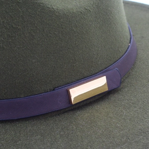 Detail of dark green wool felt hat with purple leather belt and golden metal buckle