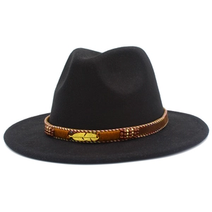 Detail of black wool fedora featuring a woven brown band and golden feather pendant