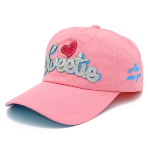 Détail d'une casquette rose avec broderie pailletée Sweetie et un cœur en sequins rouges