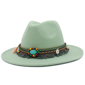 Détail d'un chapeau en feutre vert menthe avec perles turquoise et pendentif pièce argent